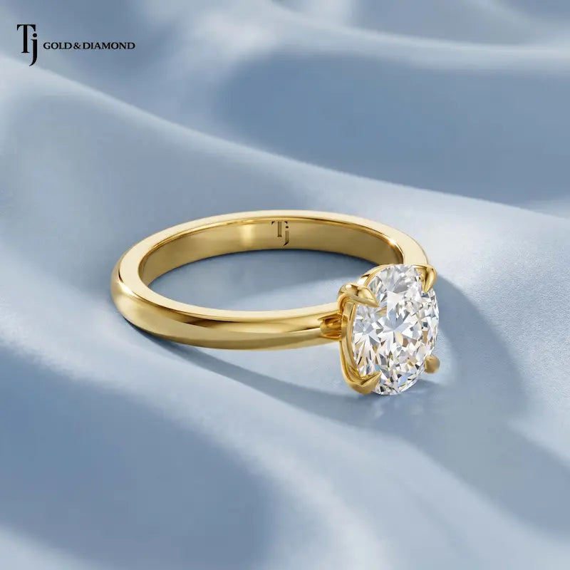 Side view of a 1.5 carat oval cut lab-grown diamond solitaire engagement ring in 18kt yellow gold on blue satin