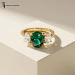 Front view of an oval lab-created emerald and diamond trilogy engagement ring in 18kt yellow gold.