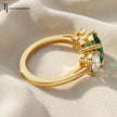Side View of an oval lab-created emerald trilogy engagement ring in 18kt yellow gold with oval lab-grown diamond side stones and an open basket setting.