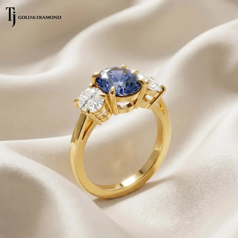 Angled View of an Oval Cut Lab-Created Blue Sapphire & Lab-Grown Diamond Trilogy Ring in 18kt yellow gold highlighting the elevated basket setting and oval diamonds.