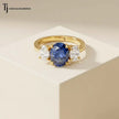 Oval Cut Lab-Created Blue Sapphire & Lab-Grown Diamond Trilogy Ring in 18kt yellow gold featuring an oval royal blue sapphire with oval lab-grown diamond side stones.