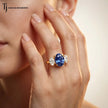 Model wearing an Oval Cut Lab-Created Blue Sapphire & Lab-Grown Diamond Trilogy Ring in 18kt yellow gold with brilliant oval side diamonds.