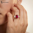 Model wearing an oval cut lab-created ruby trilogy engagement ring in 18kt yellow gold with oval lab-grown diamond side stones.