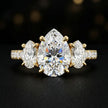 Front view of a pear cut three-stone lab-grown diamond engagement ring in 18kt yellow gold with diamond shoulders