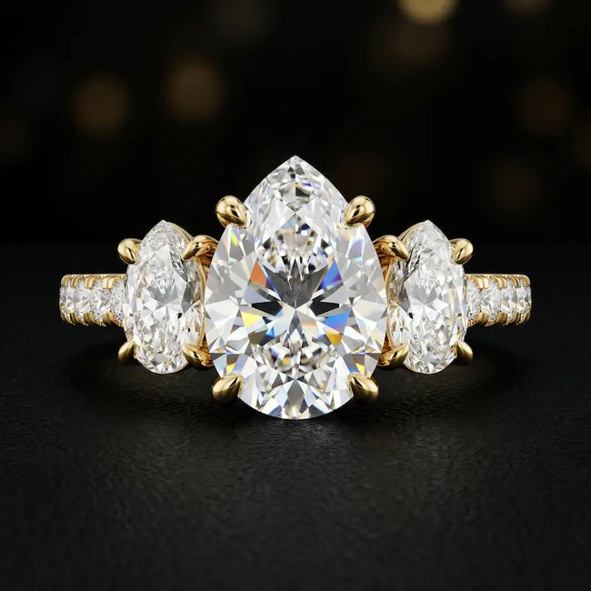 Front view of a pear cut three-stone lab-grown diamond engagement ring in 18kt yellow gold with diamond shoulders