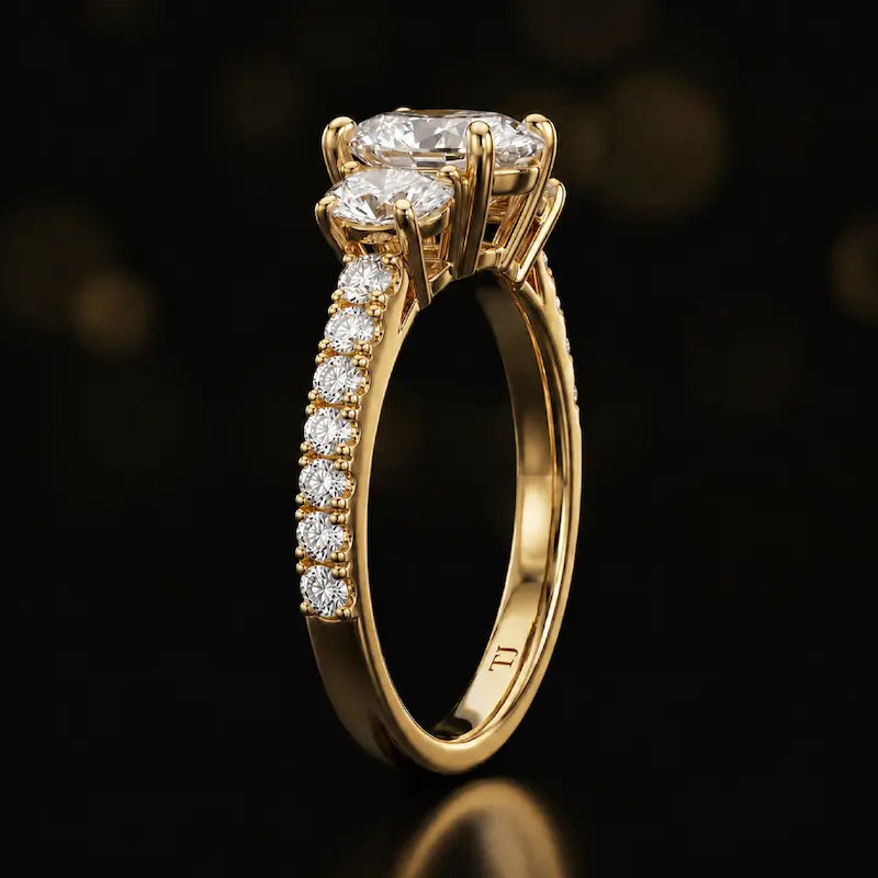 Side profile of a pear cut three-stone lab-grown diamond engagement ring in 18kt yellow gold showing the diamond band
