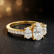 Side view of a pear cut three-stone lab-grown diamond engagement ring in 18kt yellow gold with diamond shoulders