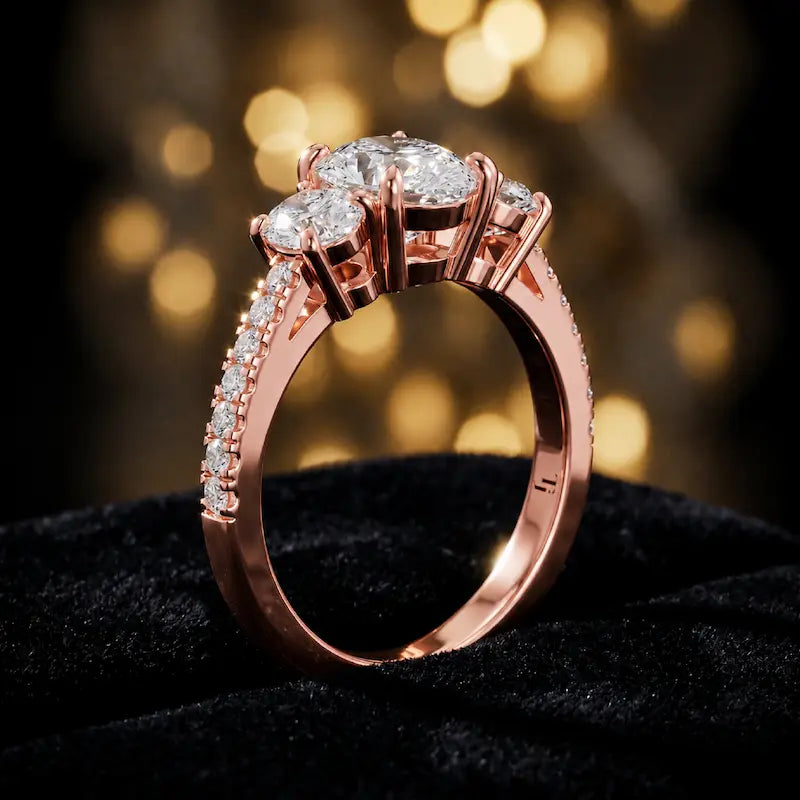 Angled view of a pear cut three-stone lab-grown diamond engagement ring in 18kt rose gold with diamond shoulders