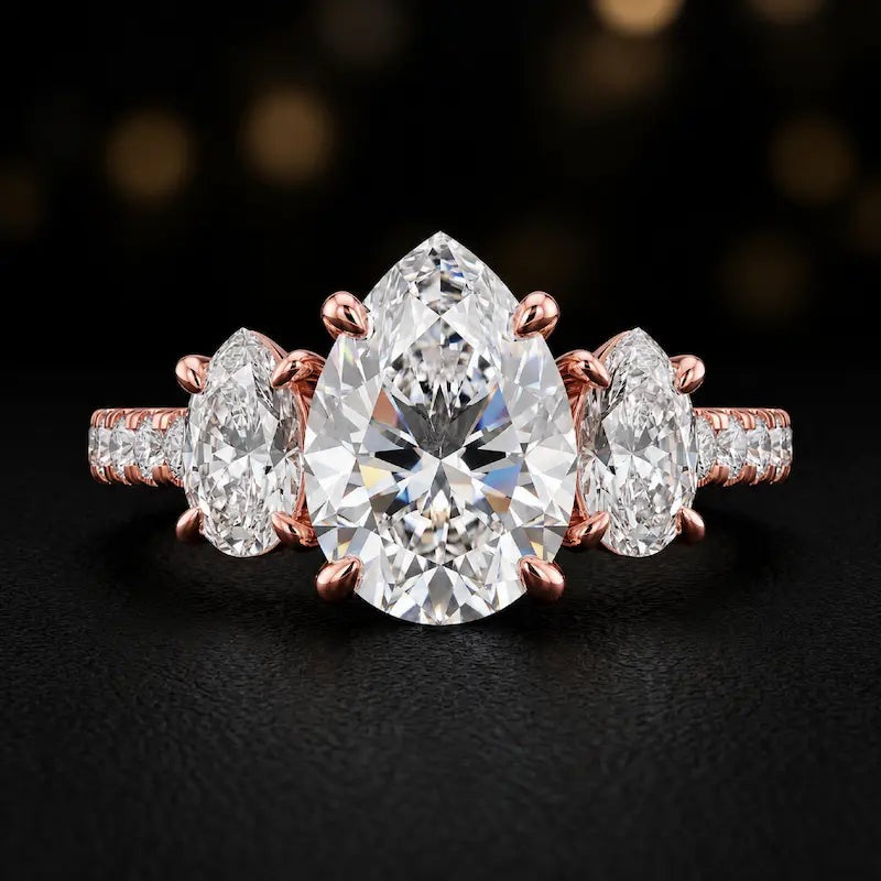 Front view of a pear cut three-stone lab-grown diamond engagement ring in 18kt rose gold with diamond shoulders