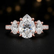 Front view of a pear cut three-stone lab-grown diamond engagement ring in 18kt rose gold with diamond shoulders