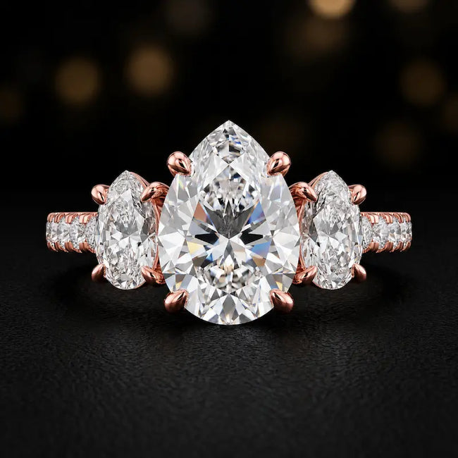 Front view of a pear cut three-stone lab-grown diamond engagement ring in 18kt rose gold with diamond shoulders