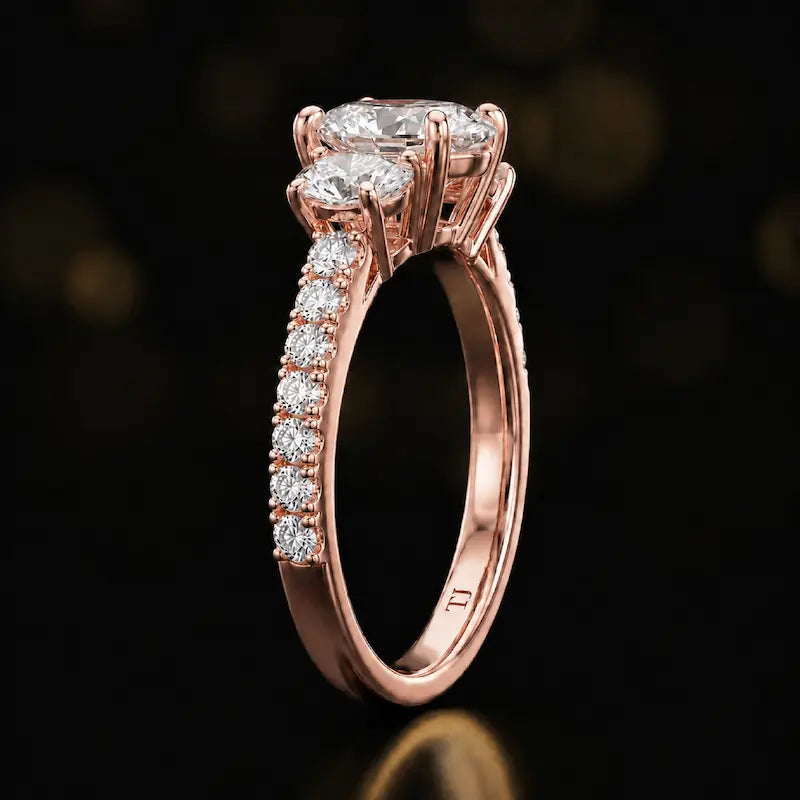 Side profile of a pear cut three-stone lab-grown diamond engagement ring in 18kt rose gold showing the diamond band