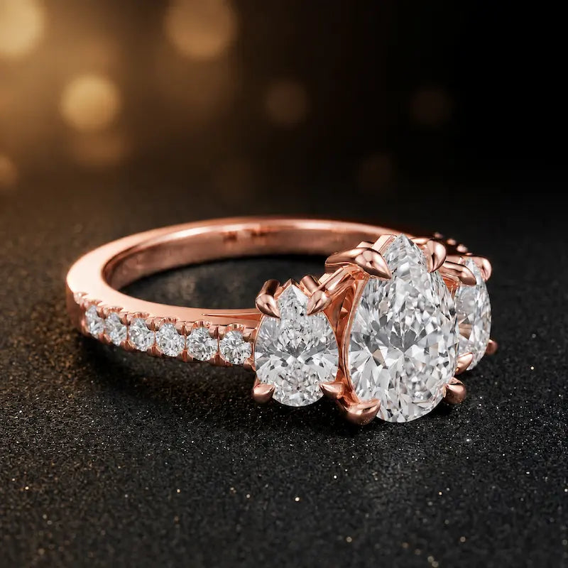Side view of a pear cut three-stone lab-grown diamond engagement ring in 18kt rose gold with diamond shoulders