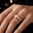 Pear cut three-stone lab-grown diamond engagement ring in 18kt rose gold with diamond shoulders worn on hand