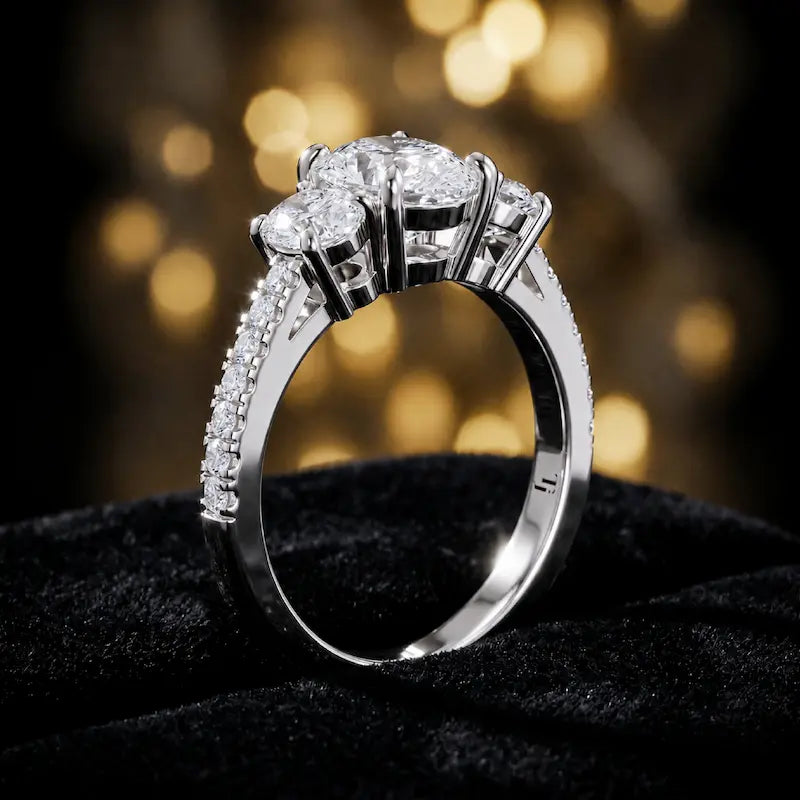 Angled view of a pear cut three-stone lab-grown diamond engagement ring in 18kt white gold with diamond shoulders