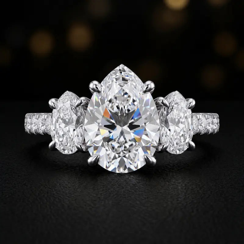 Front view of a pear cut three-stone lab-grown diamond engagement ring in 18kt white gold with diamond shoulders