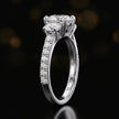 Side profile of a pear cut three-stone lab-grown diamond engagement ring in 18kt white gold showing the diamond band