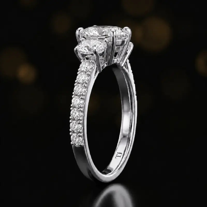 Side profile of a pear cut three-stone lab-grown diamond engagement ring in 18kt white gold showing the diamond band