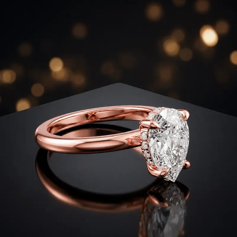 Angled view of 4-claw pear cut engagement ring with hidden halo in 18kt rose gold