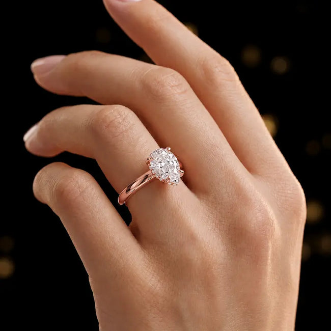 4-claw pear cut engagement ring with hidden halo in 18kt rose gold, worn on hand