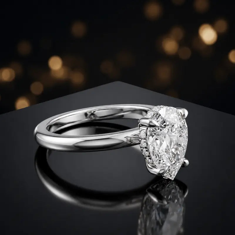 Angled view of 4-claw pear cut engagement ring with hidden halo in 18kt white gold