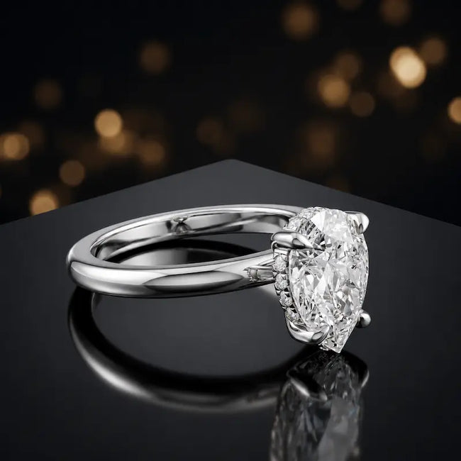 Angled view of 4-claw pear cut engagement ring with hidden halo in 18kt white gold