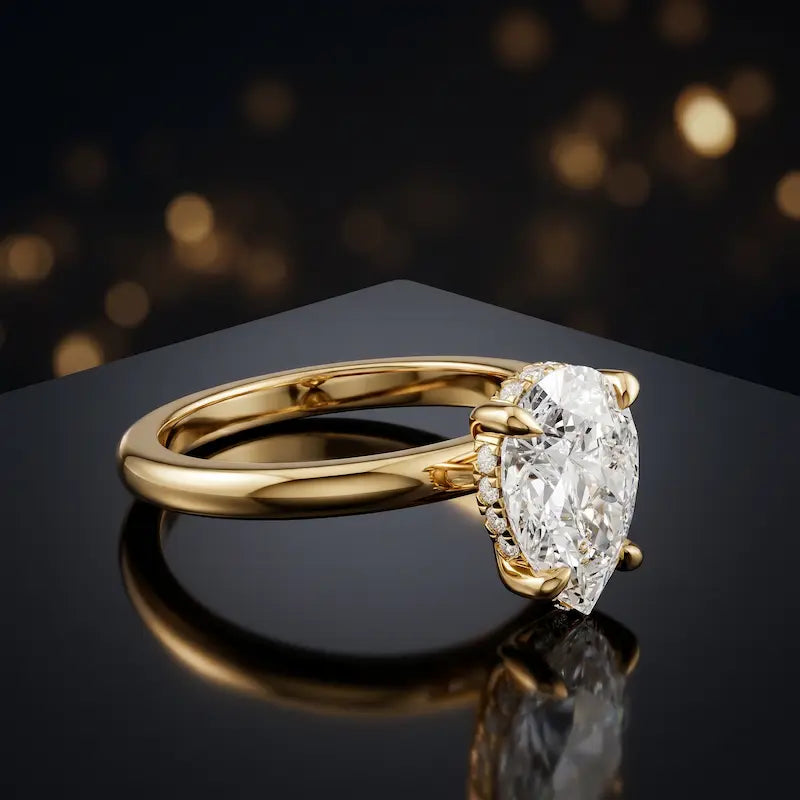 Angled view of 4-claw pear cut engagement ring with hidden halo in 18kt yellow gold