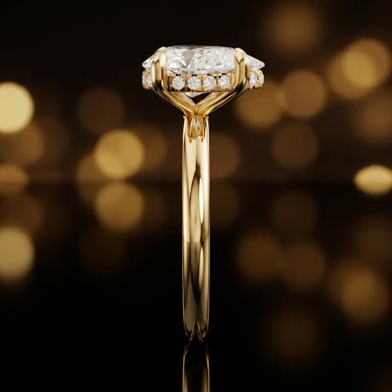 Side profile of 4-claw pear cut engagement ring with hidden halo in 18kt yellow gold