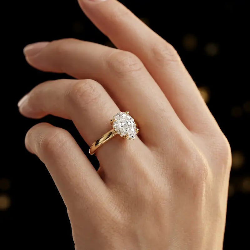 4-claw pear cut engagement ring with hidden halo in 18kt yellow gold, worn on hand