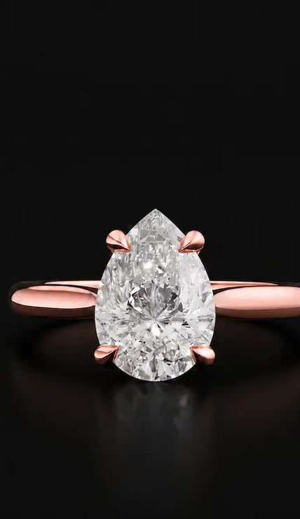 Front view of a 1.5 carat pear cut diamond solitaire engagement ring in an 18kt rose gold 4 claw setting by TJ Diamond