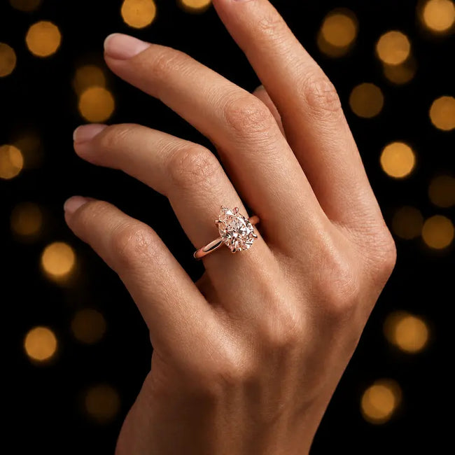 1.5 carat pear cut diamond solitaire engagement ring in an 18kt rose gold 4 claw setting worn on a hand, by TJ Diamond