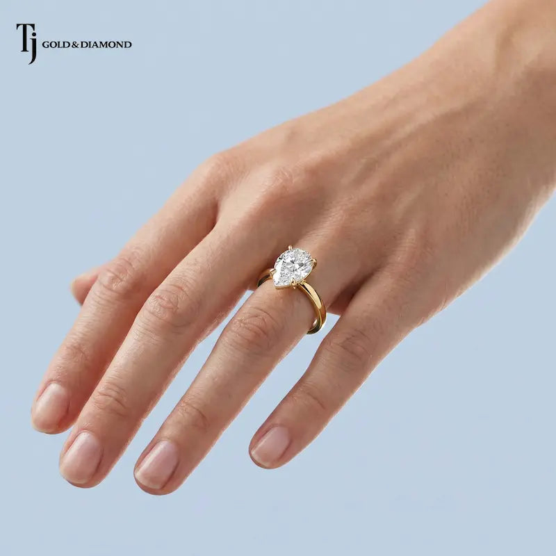 1.5 carat pear cut lab-grown diamond solitaire engagement ring in 18kt yellow gold worn on hand