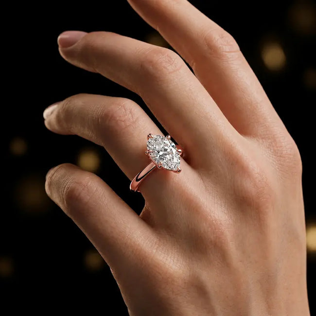 1.5 carat pear cut diamond solitaire engagement ring in an 18kt rose gold 6 claw setting worn on a hand, by TJ Diamond