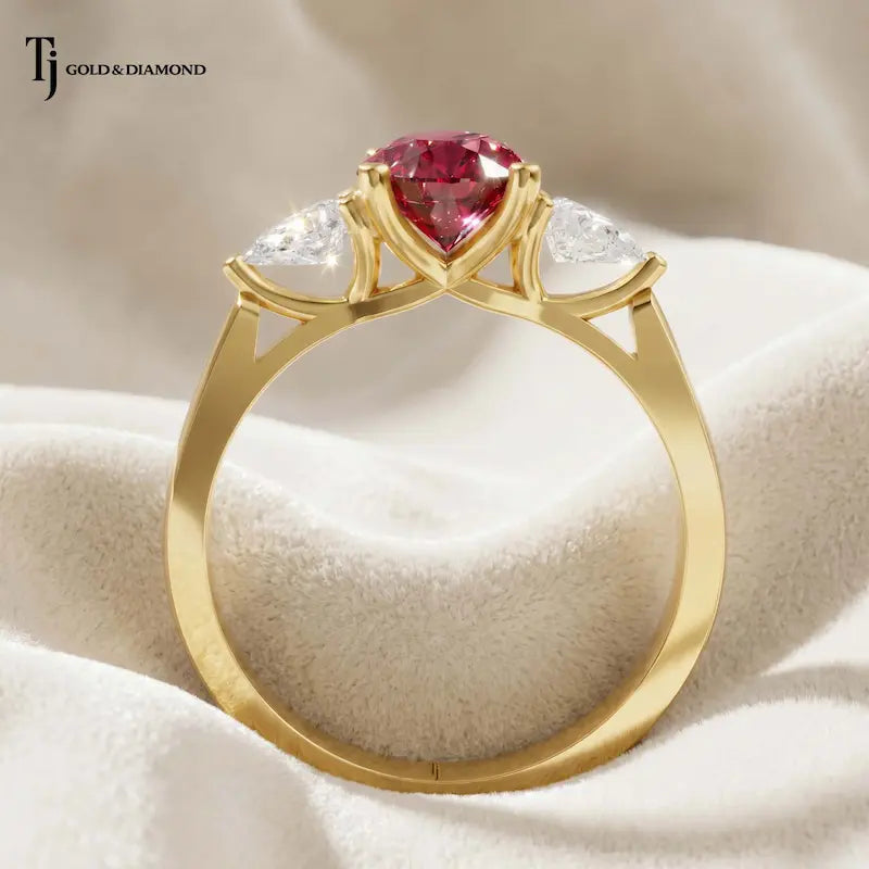 Rear view of a pear cut lab-created ruby trilogy engagement ring in 18kt yellow gold showcasing the open four claw basket setting and pear cut lab-grown diamond side stones.