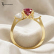 Rear view of a pear cut lab-created ruby trilogy engagement ring in 18kt yellow gold showcasing the open four claw basket setting and pear cut lab-grown diamond side stones.
