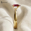 Side profile of a pear cut lab-created ruby trilogy engagement ring in 18kt yellow gold with pear cut lab-grown diamond side stones and a four claw basket setting.