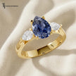 Pear Cut Lab-Created Blue Sapphire & Lab-Grown Diamond Trilogy Ring in 18kt yellow gold featuring a pear-shaped royal blue sapphire with pear-shaped lab-grown diamond side stones.