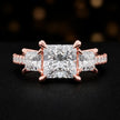 Front view of a princess cut three-stone lab-grown diamond engagement ring in 18kt rose gold with diamond shoulders