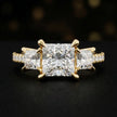 Front view of a princess cut three-stone lab-grown diamond engagement ring in 18kt yellow gold with diamond shoulders