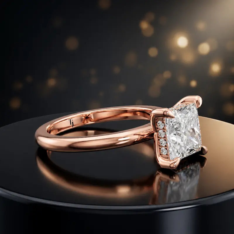 Angled view of 4-claw princess cut engagement ring with hidden halo in 18kt rose gold