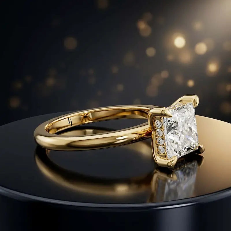 Angled view of 4-claw princess cut engagement ring with hidden halo in 18kt yellow gold
