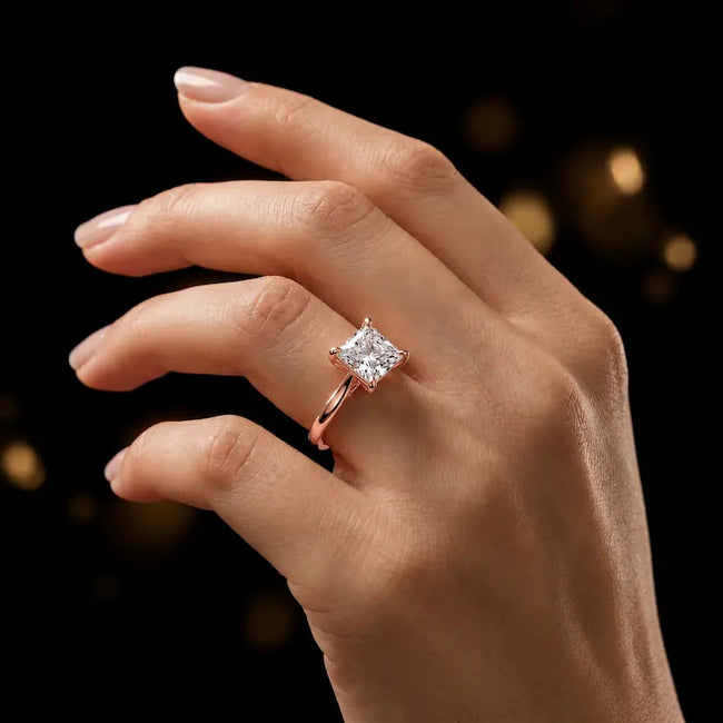 1.5 carat princess cut diamond solitaire engagement ring in an 18kt rose gold 4 claw setting worn on a hand, by TJ Diamond
