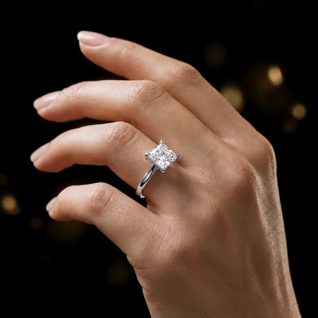 1.5 carat princess cut diamond solitaire engagement ring in an 18kt white gold 4 claw setting worn on a hand, by TJ Diamond