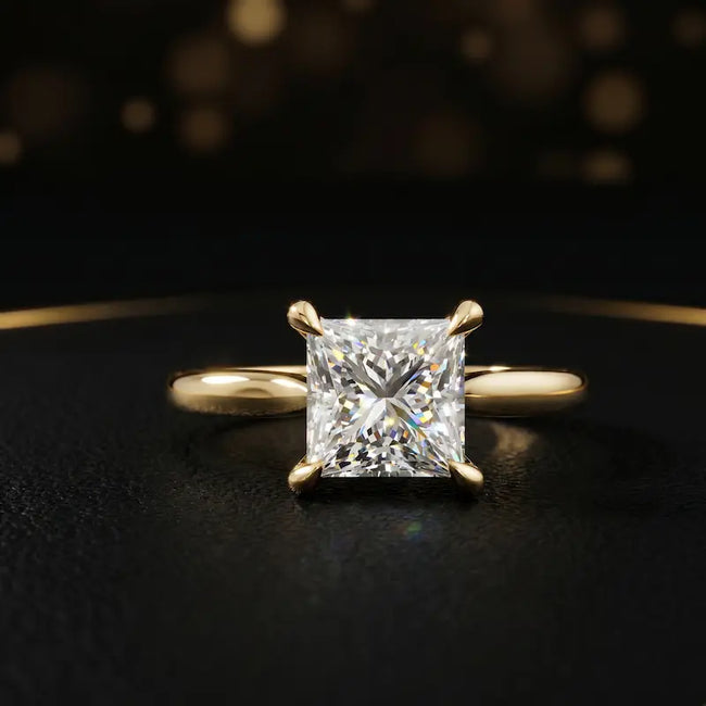 Front view of a 1.5 carat princess cut diamond solitaire engagement ring in an 18kt yellow gold 4 claw setting by TJ Diamond
