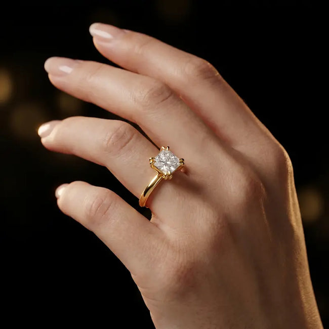 1.5 carat princess cut diamond solitaire engagement ring in an 18kt yellow gold 4 double claw setting worn on a hand, by TJ Diamond
