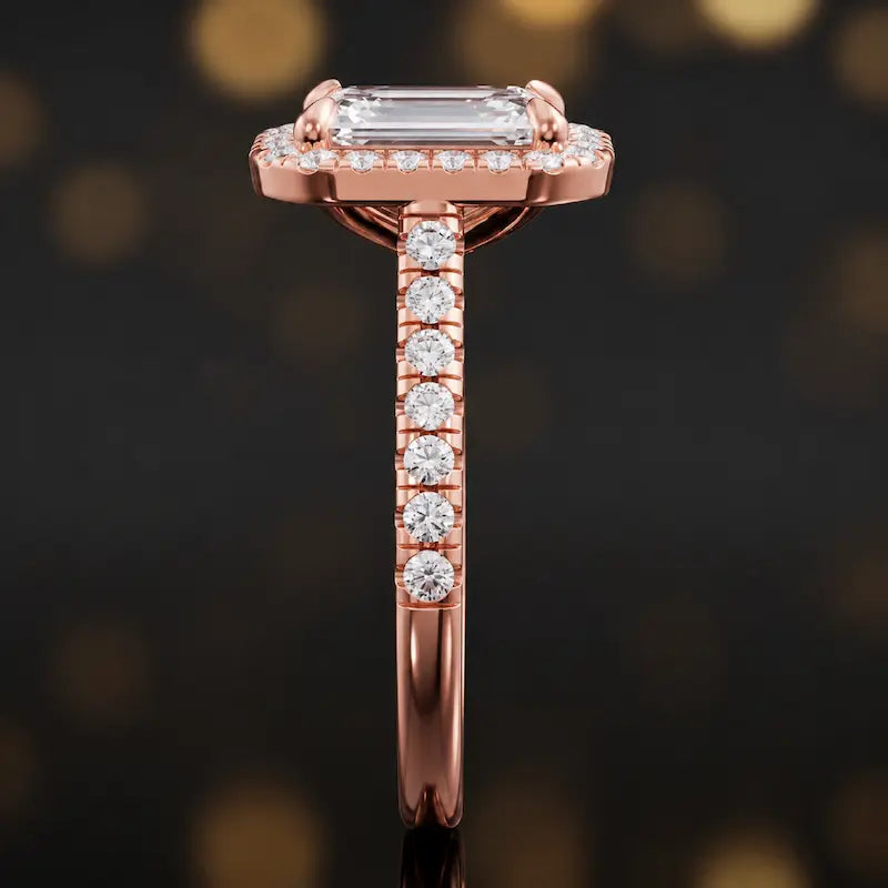 Side profile of an emerald cut halo lab-grown diamond engagement ring with diamond-set shoulders in 18kt rose gold.