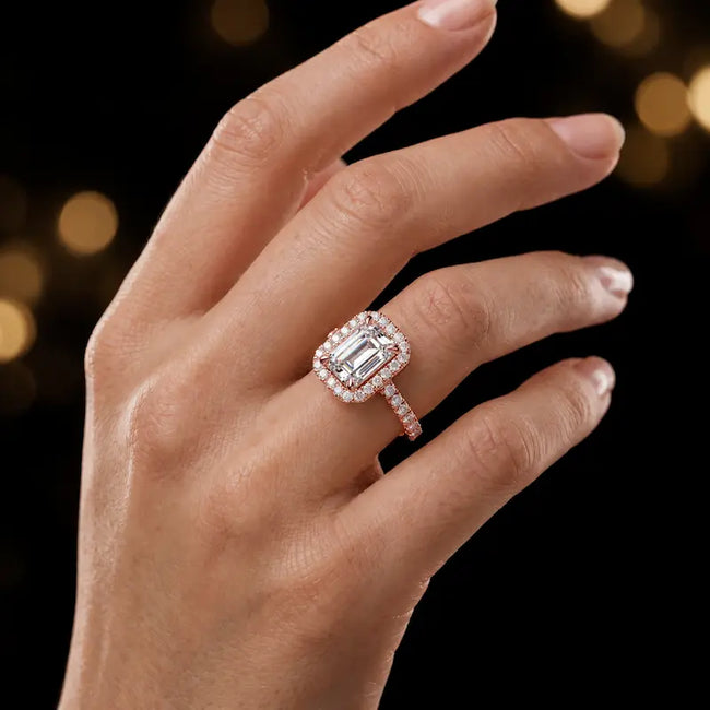 Emerald cut halo lab-grown diamond engagement ring worn on hand in 18kt rose gold.