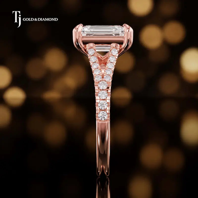 Side profile of an emerald cut split shank lab-grown diamond engagement ring with diamond-set shoulders in 18kt rose gold.