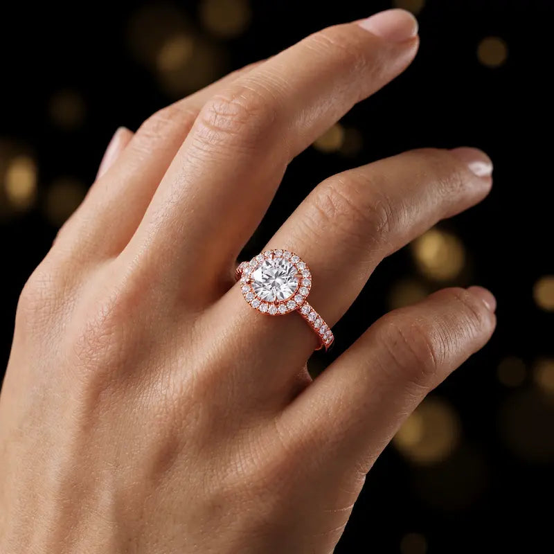 Round cut halo lab-grown diamond engagement ring worn on hand in 18kt rose gold.