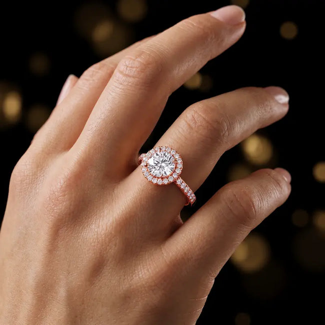 Round cut halo lab-grown diamond engagement ring worn on hand in 18kt rose gold.